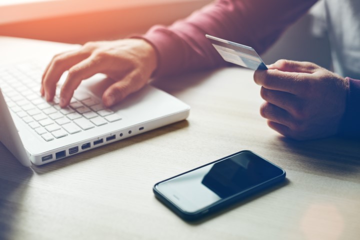 Man with credit card in hand and smartphone using laptop. Online