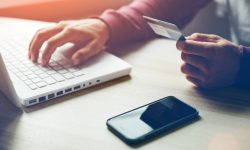 Man with credit card in hand and smartphone using laptop. Online